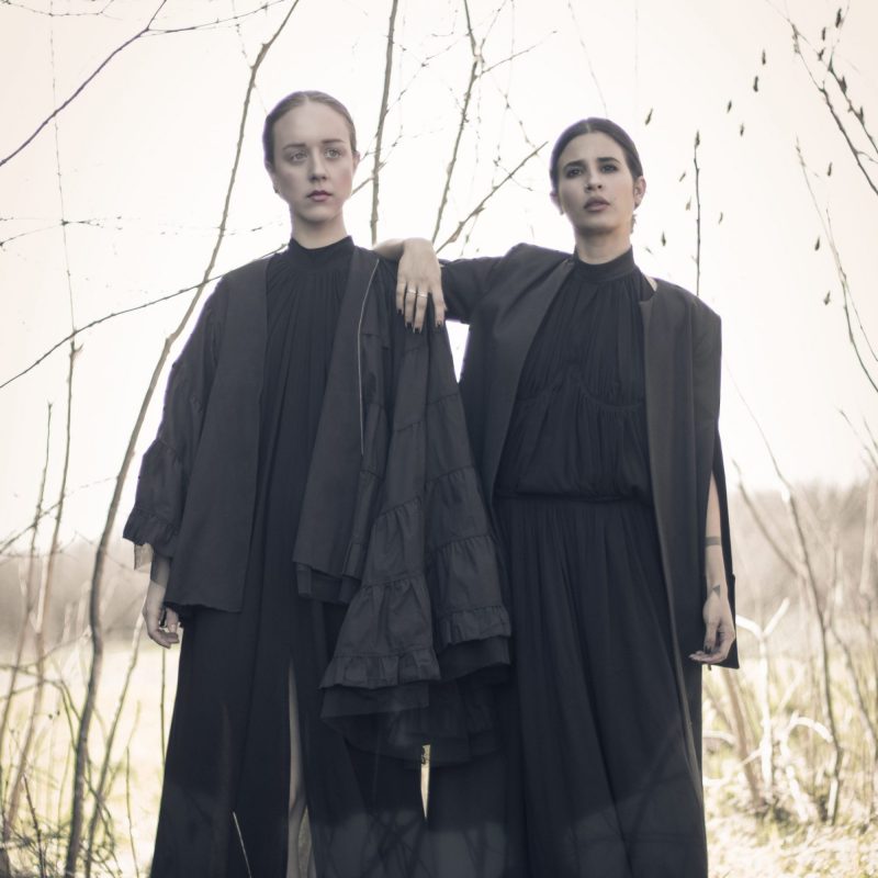 Two women wearing black organic dresses