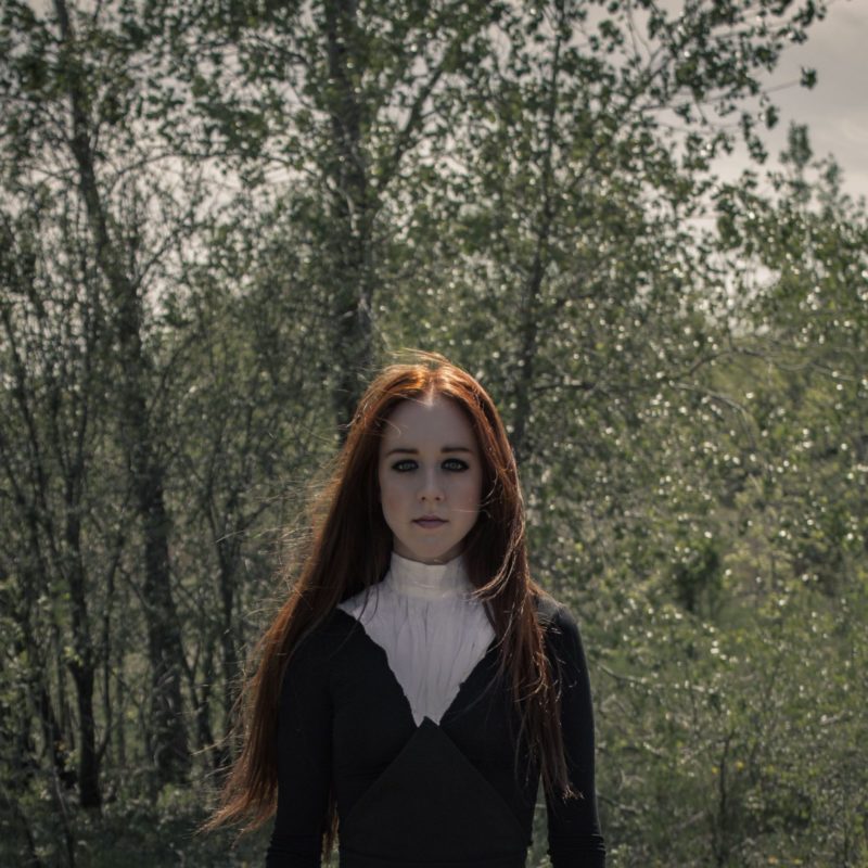 Woman in front of trees wearing black organic dress with white color