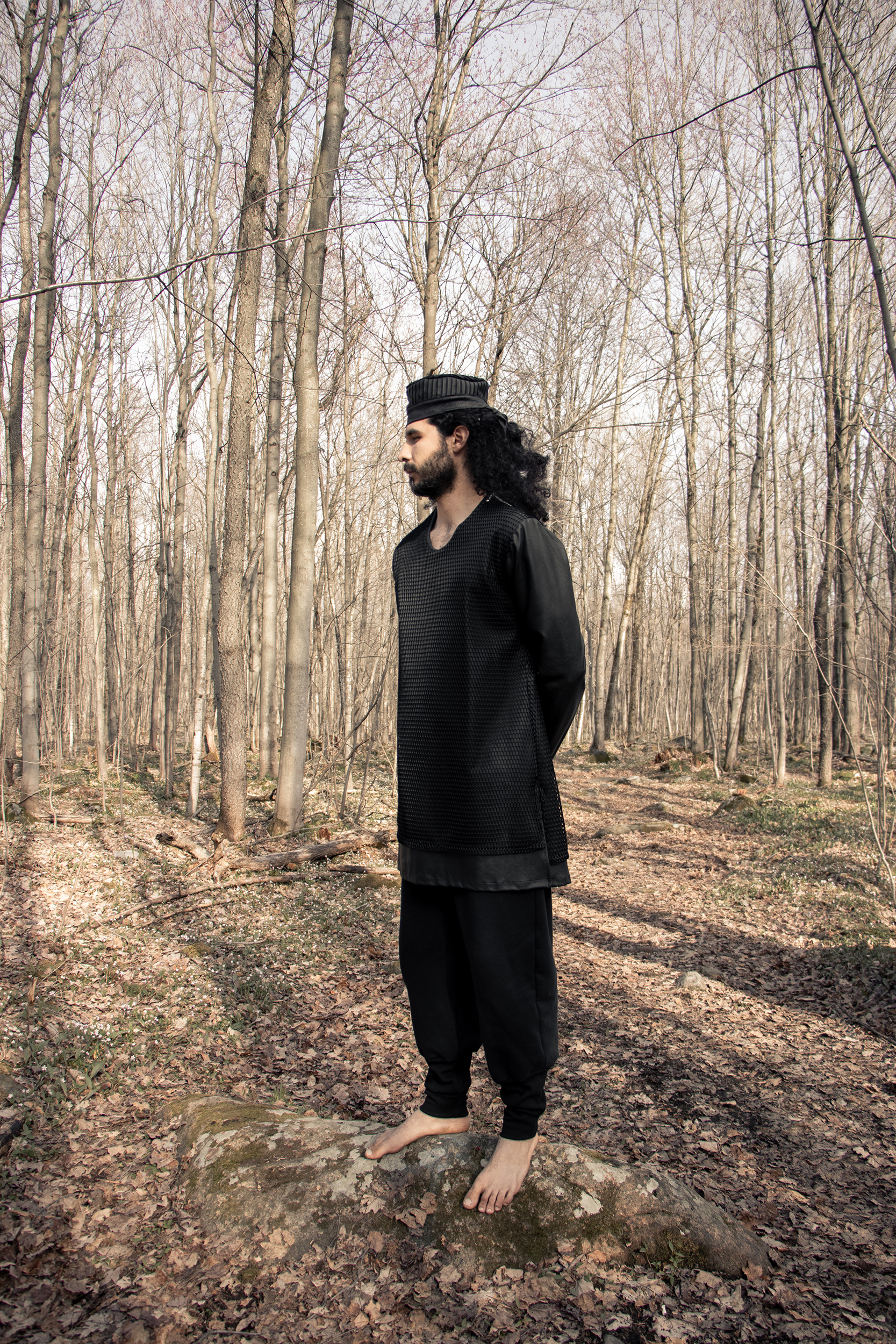 Man wearing a black tunic with black organic sweatpants in the woods